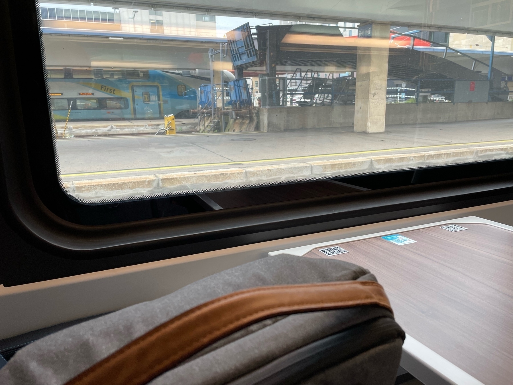 view out of a train showing the platform and another train in the background 